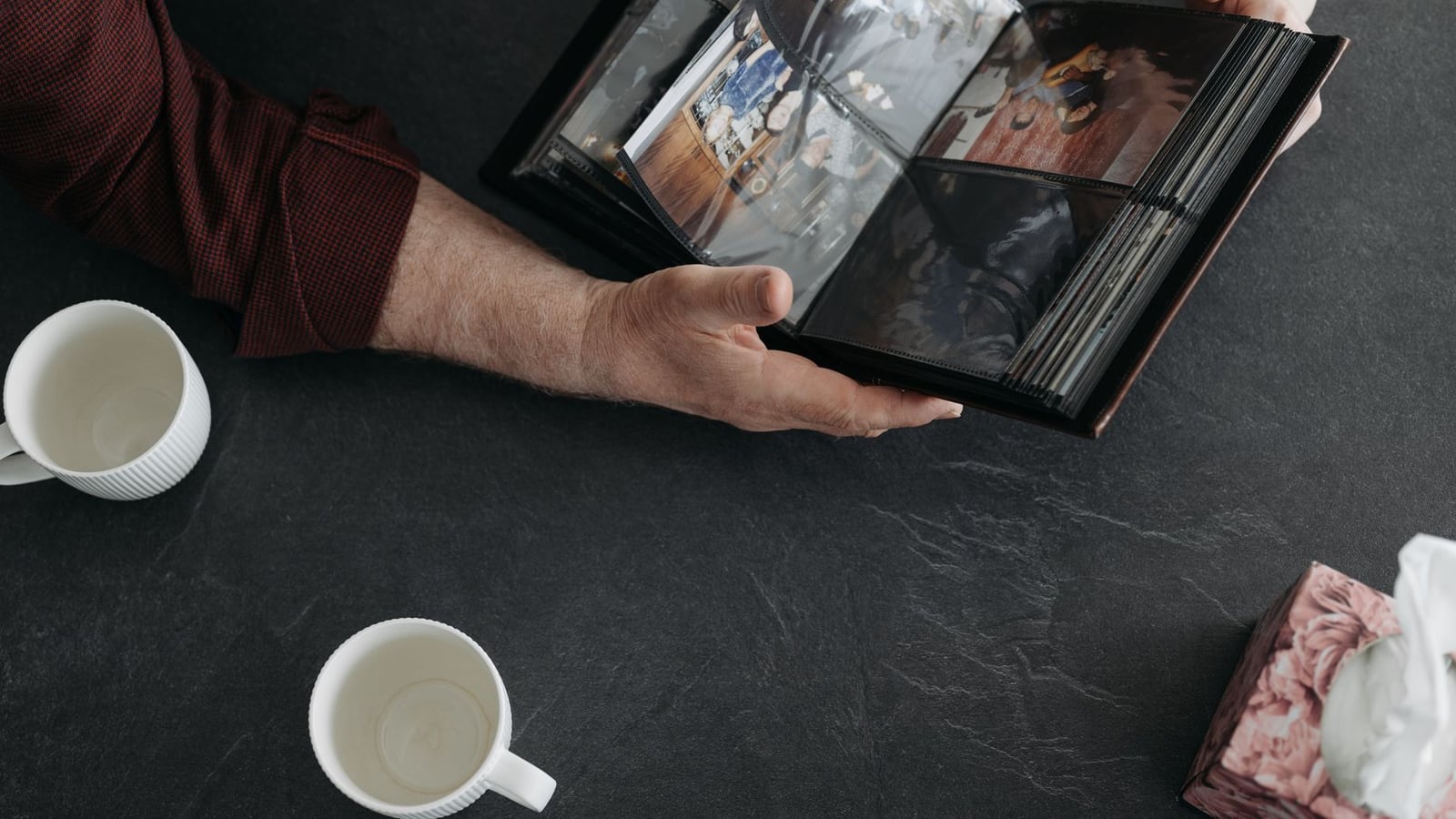 Hands carefully placing vintage family photographs into a handmade archival album.
